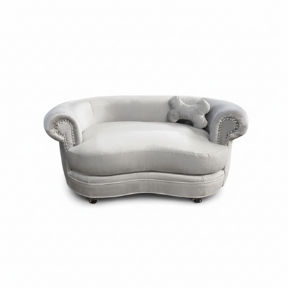 Gray plush dog bed with decorative armrests on a white background