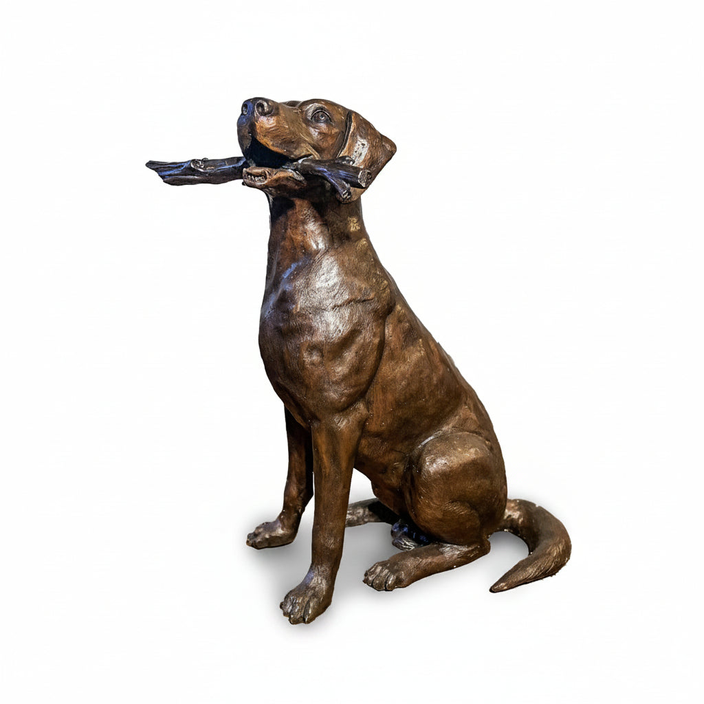 Bronze statue of a dog holding a stick on a white background